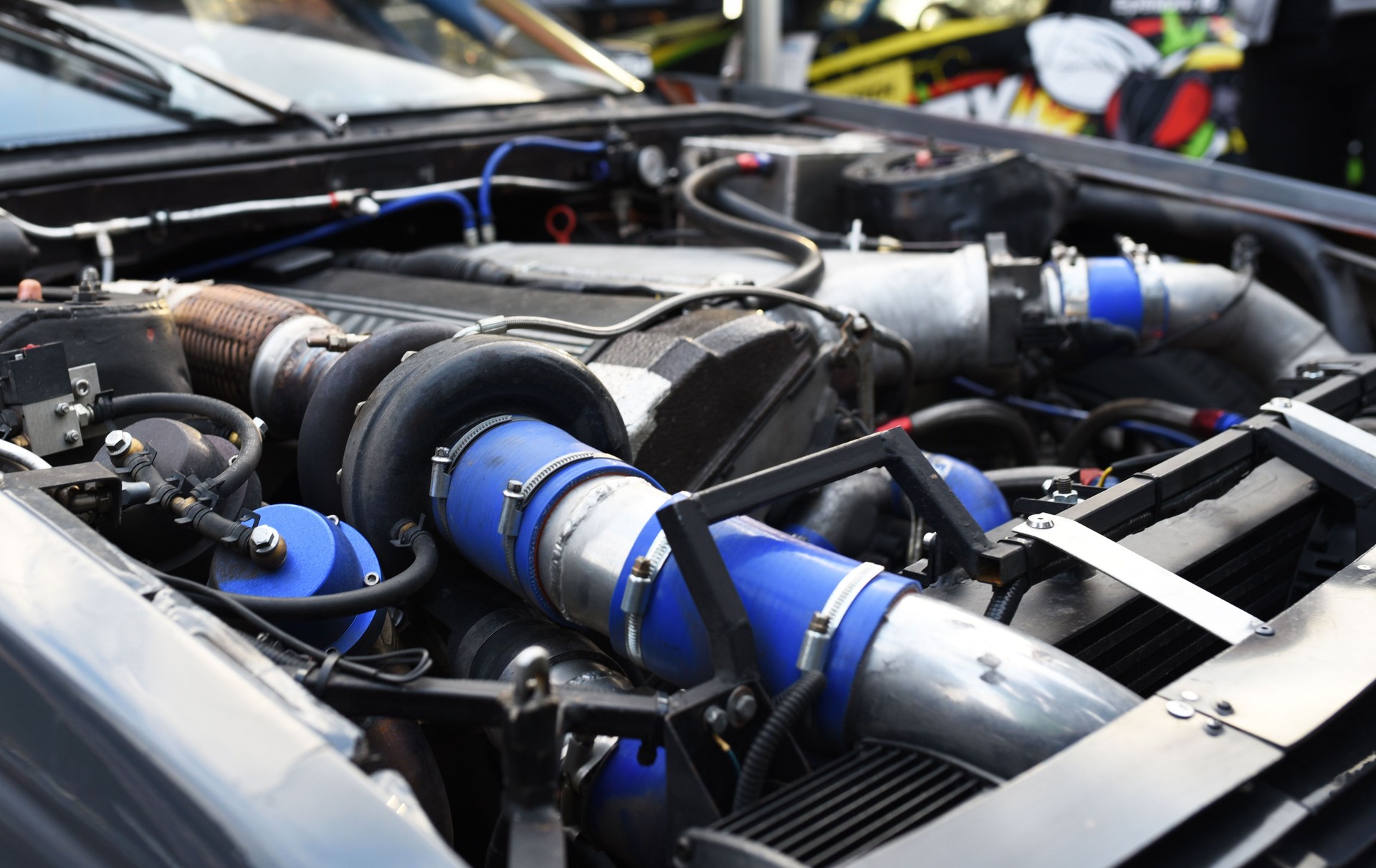 Sports car engine with turbine. An open race car hood on a pit stop while racing on a race track.